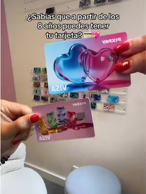 A woman holds two Pixpay cards, one with heart shapes and the other with gummy bear illustrations, in front of a display of cards. The backdrop includes a white wall and a few decorative items, with the text overlayed on the image.