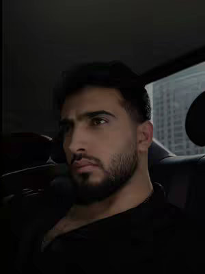 The cover image features a close-up of a man in a car, likely the driver or a passenger. He has dark hair and a trimmed beard. The lighting is dim, coming from the side, casting shadows and giving the image a moody feel. The background is blurred, suggesting the focus is on the man. The car interior is visible, with the headrest and a glimpse of a building through the window.