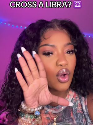 A woman with long, dark, curly hair and makeup is the central focus. She holds her hand up, fingers spread, as if gesturing towards the viewer. The background is an out-of-focus purple with some blue lights. Text overlays say "CROSS A LIBRA?" with the Libra zodiac symbol following.