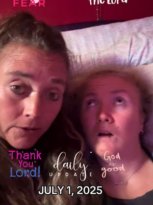 A selfie-style image featuring two women, likely in a bedroom setting, with text overlays. The woman on the left gazes directly at the camera, while the woman on the right looks upward with a surprised expression. Pink and white text overlays include phrases like 'Thank You Lord!', 'God is good', and 'daily UPDATE JULY 1, 2025'. The background is a warm, dark red, and the lighting appears soft and diffused.