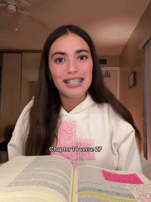 The cover image showcases a young woman with long brown hair, wearing a white hoodie. She is smiling and has braces on her teeth. She is sitting in a well-lit room with a book open in front of her. Text overlay at the bottom says "Chapter 14 verse 27".