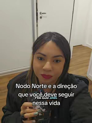 A selfie-style video cover with a woman in the foreground holding a card. She has long, highlighted hair, red lipstick, and is wearing a dark jacket. The background is a minimalist, bright room with white doors and a wall. Text overlays are placed on the image.