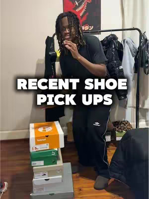 A person in a black t-shirt and black sweatpants stands in a room with a rack of clothing in the background with a blurred look on their face, in front of a stack of shoe boxes with a layer of text on top that says "RECENT SHOE PICK UPS."