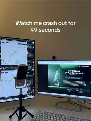 The image shows a desktop setup with two computer monitors. The left monitor displays a stock trading chart, while the right shows a certificate. A microphone on a stand is in front of the monitors, positioned between them. A keyboard sits on the desk.