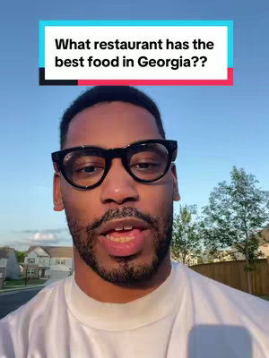 A man wearing glasses is centered, his face filling most of the frame. Above him, a rectangular text overlay reads 'What restaurant has the best food in Georgia??' The background suggests an outdoor setting with trees and houses.