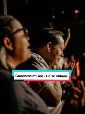 The image shows a crowd of people in a dimly lit room, likely a church or similar venue. The focus is on a man singing with his eyes closed and arms raised, with other figures in the background. The lighting is warm, creating a sense of intimacy and emotion. A text overlay at the bottom provides the song title and artist.