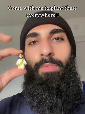 A man with a beard holds a small figurine of Jesus in front of his face.