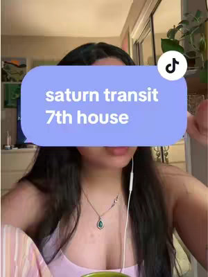 A selfie-style shot featuring a person looking at the camera, with a light blue rounded rectangle overlay covering the top half of the frame. The text overlay states: "saturn transit 7th house". The person has long dark hair, a thin necklace, and is wearing a light-colored top. The background is blurred and shows a room with a window. There's a TikTok logo in the top right corner.