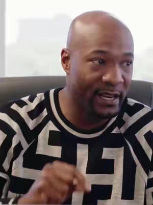 The cover image shows a bald Black man with a serious expression. He's wearing a black and white geometric patterned sweater. The background is blurred, suggesting an indoor setting.