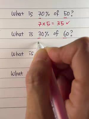 A person's hand writing math problems on lined paper. The top line says 'What is 70% of 50?' and below it '7x5 = 35'. The hand continues to write another percentage question.