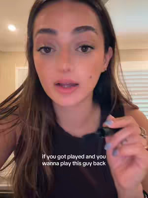 A selfie-style video featuring a woman with long brown hair. She is speaking directly to the camera, with text overlayed over the bottom of the image. The setting appears to be indoors, possibly a home, with a neutral wall in the background.