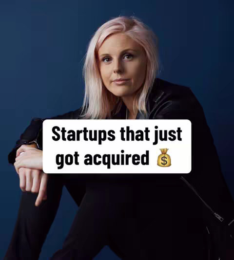 A woman with pink hair and a black jacket is the subject of this photo. A white banner with text is in the lower center: "Startups that just got acquired" with a money bag emoji beside it. The background is a solid dark blue.