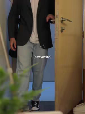 A man in a dark blazer, white shirt, and light-wash jeans is opening a light-colored door. The shot is from the mid-thigh up, with part of a wall and some greenery visible on the left. The text overlay says "(boy version)".