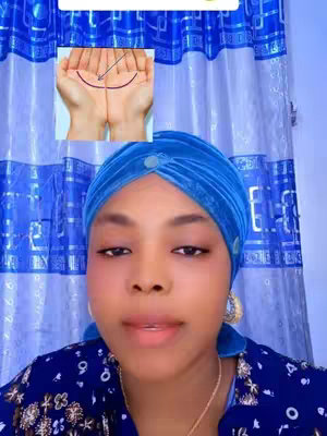 The image features a woman gazing at the viewer, framed from the chest up. She is wearing a blue head covering and a dark blue blouse with a floral pattern. Against a backdrop of blue curtains, the woman is the focus of the image, and there is a small inset image within the frame. Inset in the background is a picture of a palm reading.