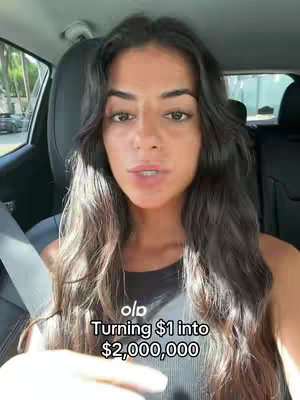 A woman filming herself from the inside of a car. The background includes the car's interior and a glimpse of an outside road scene.
