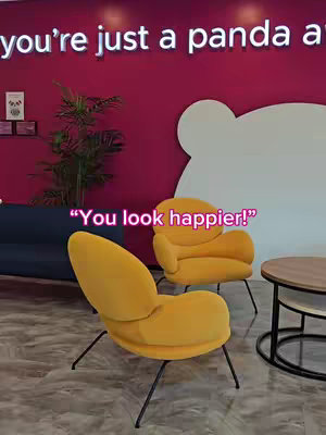 The image captures a vibrant interior scene, featuring two yellow armchairs positioned in front of a pink wall. In the background, there is a round wooden table and a dark blue sofa. The cover image has a large "panda" logo on the wall and a text overlay that says "You look happier!".