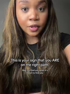 A woman with long, wavy brown hair looks directly at the camera. Text overlays in white font. The background is a blurred, neutral color.