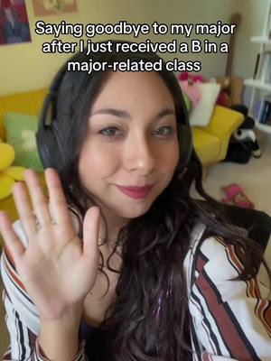 A woman with dark hair and headphones waves at the camera, with text overlaying the image, and a blurred background.