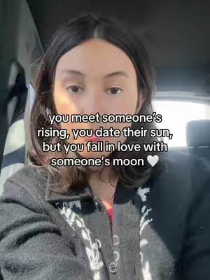 A woman with dark hair in a car, looking at the camera with text overlayed.