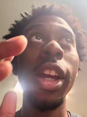 A close-up shot of a young Black man looking upwards with an open mouth and an animated, potentially surprised expression. A finger is in the foreground, pointing towards the man, further emphasizing his expression and the video title's hook, "Jesus help me". The composition uses sunlight from above, highlighting the man's face.