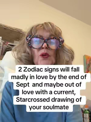 A woman with short gray hair, large bedazzled glasses, and a blue long sleeve shirt is looking directly into the camera. White text is overlaid on top of her. The background appears to be a room with shelves and items scattered about.