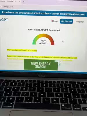 A laptop screen displaying a website interface for a text AI detection tool. The screen is light gray with the website's header visible and a section analyzing a text sample showing a circular gauge indicating 100% AI-generated content.