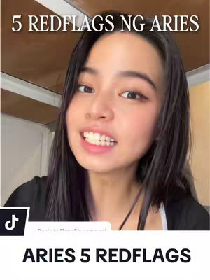 A young woman with long, dark hair is centered in this selfie-style shot. She's smiling, with her teeth visible, against a background that appears to be an interior setting. The top of the image features a text overlay that reads '5 REDFLAGS NG ARIES'. At the bottom, below the woman's face, is additional text that says 'ARIES 5 REDFLAGS'. The image also includes social media icons.