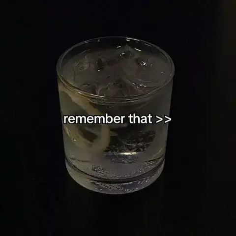 An overhead shot of a clear glass with ice cubes and a lemon slice in it against a dark background. The text overlay in white reads remember that >>.