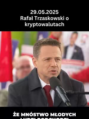 A man in a dark coat and red tie speaks into a microphone. Background elements include blurry individuals and flags. Text overlays indicate a date and topic, and a lower black bar presents additional text.