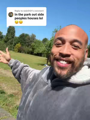 The cover image shows a man with a shaved head and a smiling face, wearing a gray hooded sweatshirt. He is positioned in front of a green grassy area with trees and a blue sky. A speech bubble from a comment is visible in the top right corner.