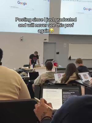 The image shows a classroom setting during a college lecture. Students are seated at desks, some with laptops open, and the professor is standing near a desk at the front. The color scheme is muted, with a focus on the people and classroom setting. Text is added to the image in a white font.