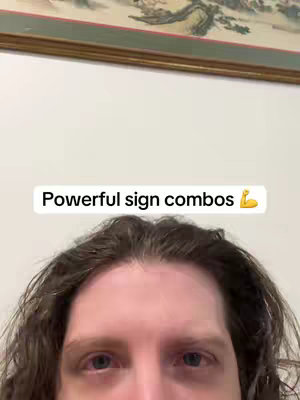 The image is a selfie-style shot focusing on a person's face with the text overlayed on it. The person, framed from the bottom of the forehead down, has mid-length, wavy brown hair. The background is a plain white wall near the bottom and an artistic painting at the top by the wall. The text overlay, in a clean, sans-serif font, reads 'Powerful sign combos' followed by a flexed bicep emoji.