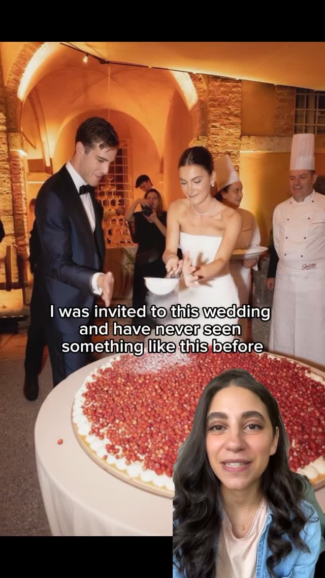 A split screen shows a woman on the bottom right smiling while looking at the camera. The other side of the screen shows a wedding scene where the bride and groom are pouring something on a giant cake. The cake is covered in red berries.