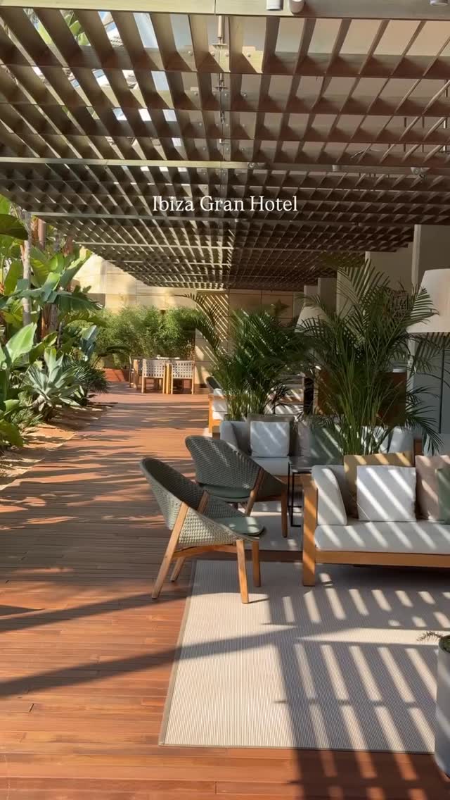 The cover image shows an outdoor seating area under a wooden pergola. The area features wooden flooring and a neutral-colored rug in front of a seating arrangement of couches and chairs. Plants and greenery add to the resort-like atmosphere. The image is well-lit.