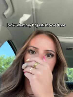 A woman is shown in the driver's seat of a car, her hands covering her mouth as if in surprise. Text at the top of the image reads, "look what my bf just showed me."