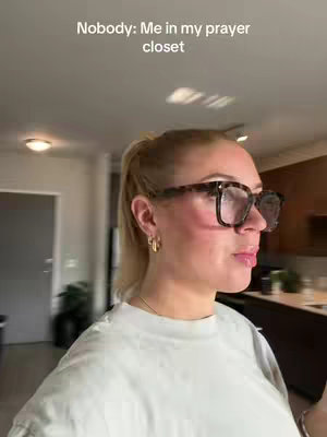 A woman with blonde hair in a ponytail, wearing glasses and a light-colored t-shirt, stands in front of a bright interior, possibly a kitchen, with text overlaid on her face.