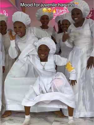 A group of women and a young girl are dressed in white outfits, posing joyfully. The group appears to be celebrating together, with several people smiling and laughing. The central figure, a young girl, strikes a dancing pose and is the focal point. The background suggest a celebration setting.