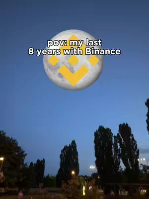 The image shows a night scene with a dark blue sky, trees, and streetlights in the foreground. A large, illuminated moon with the Binance logo in yellow is centered in the sky, creating a surreal effect, suggesting a long-term relationship with Binance.