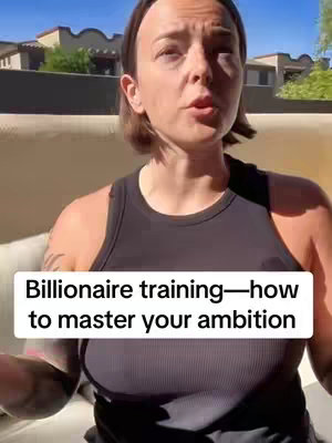 A woman with short brown hair wearing a black tank top is centered in the frame, positioned against a blurred outdoor background of buildings and foliage under a bright blue sky. Overlayed text in a white box at the bottom of the image frames the subject.