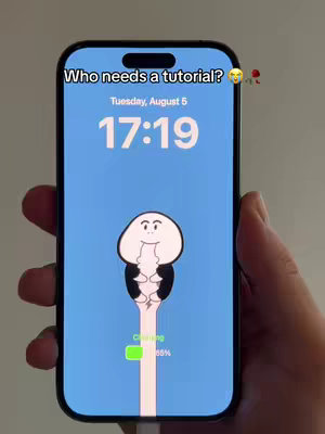 A smartphone displays a custom animated wallpaper with a cartoonish figure on a blue background. The phone is held in a hand against a neutral background. Text at the top says, 'Who needs a tutorial?'