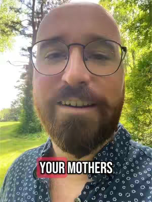A close-up shot of a man with a beard and glasses against a blurred background of trees and foliage. At the bottom, a text overlay reads "YOUR MOTHERS".