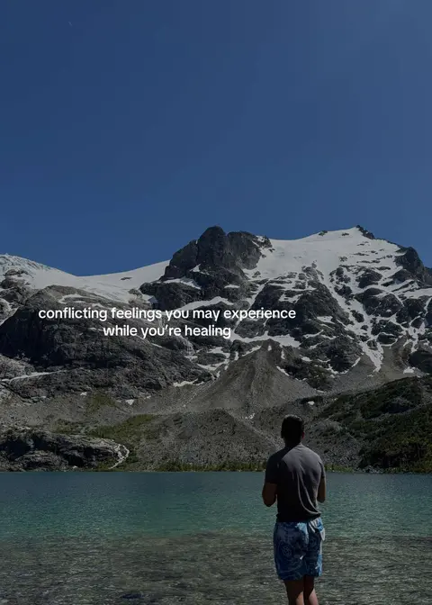 A man stands with his back to the camera, facing a serene lake and snow-capped mountains under a bright blue sky. Text overlays the scene, conveying a message about healing.
