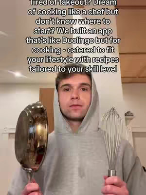 A man wearing a gray hoodie holds a frying pan and a whisk towards the camera. Text overlays the top of the image.