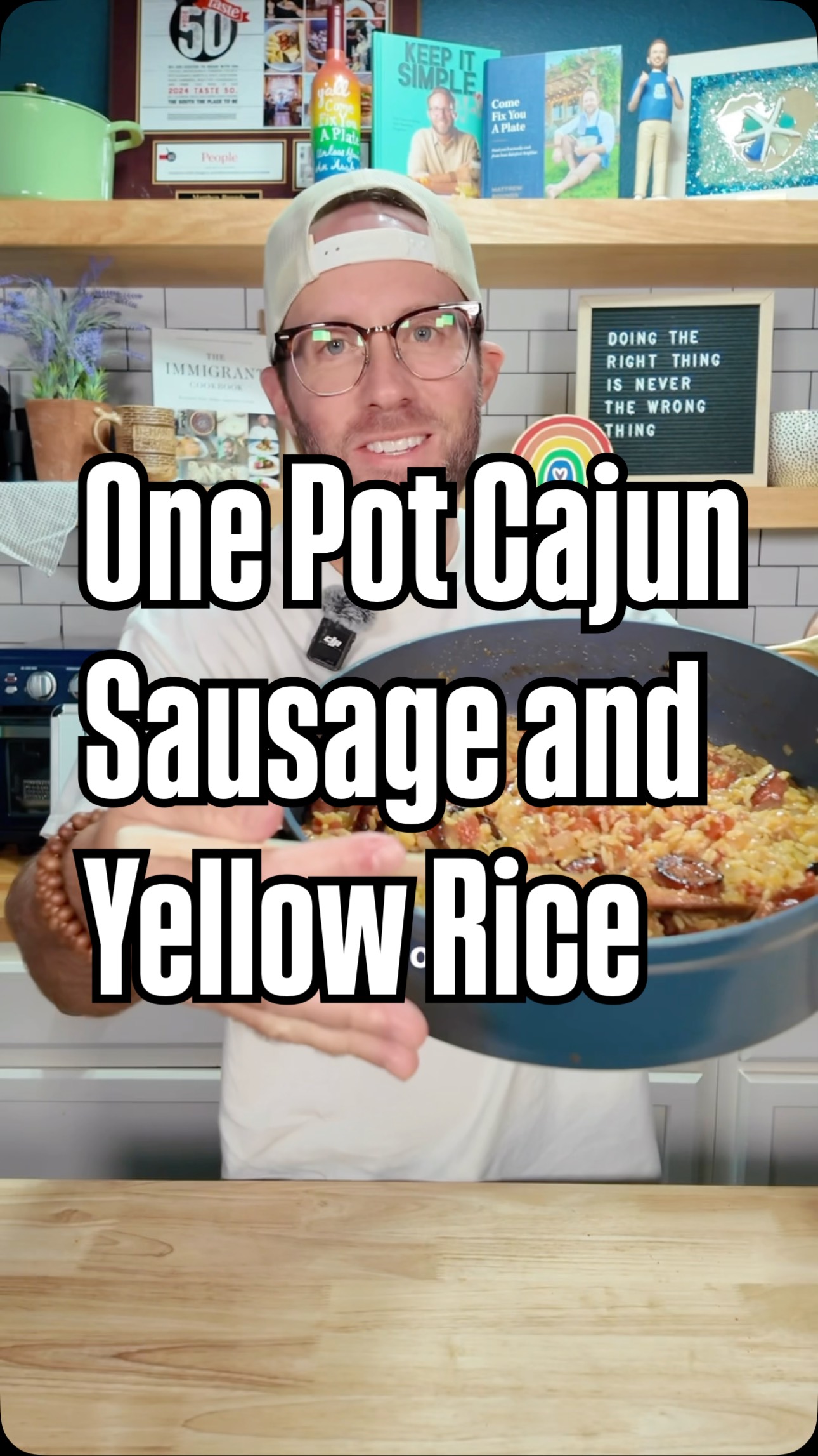 A man in glasses and a white hat is holding a blue pan with food; the text overlay says: One Pot Cajun Sausage and Yellow Rice.