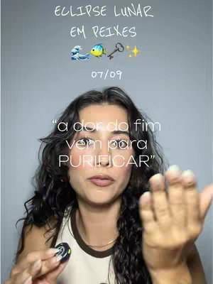 The cover image is a selfie-style shot featuring a woman with dark wavy hair as the central focus. The background is a light gray or neutral wall. Overlayed at the top of the frame is a text graphic that reads "ECLIPSE LUNAR EM PEIXES" followed by the date "07/09", and some emojis. In the foreground, below this text, is an inspirational quote in a semi-transparent text bubble. The woman is holding her palm out with the fingers extended towards the camera.