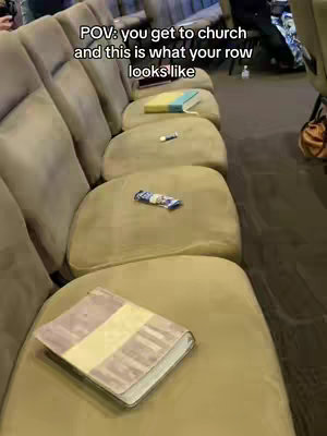 A row of church pews are shown from a low angle, with objects like books, a pen, and a candy bar, placed on the seats as though to reserve them. The composition is simple, focusing on the details of the items placed on the seats, like books and other items. The lighting appears natural.
