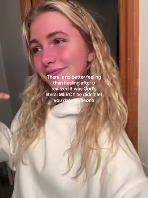A young woman is looking towards the left with a slight smile on her face. She is wearing a white hoodie with her blonde hair down. Text overlayed on the image reads, "There is no better feeling than healing after u realized it was God's literal MERCY he didn't let you date someone."
