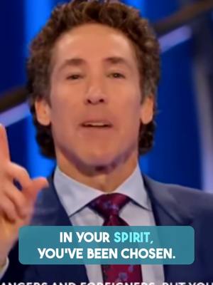 A medium shot of a man facing the camera, smiling and gesturing with his right hand. He is wearing a blue suit with a light blue collared shirt and a patterned tie. Above him is a text overlay and a dark background.
