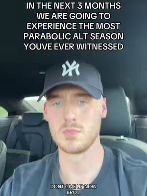 A selfie-style shot of a young man in a car. He's wearing a black baseball cap with a white logo and a dark t-shirt. Text overlays are present. The background shows the interior of the car.