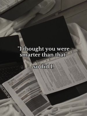 The image shows a close-up of a desk or bed with office supplies. A laptop is to the left, with papers spread around the desk. There's a binder open and some documents and papers are present on the surface, suggesting work or study materials. Above the documents, a text overlay with a quote.